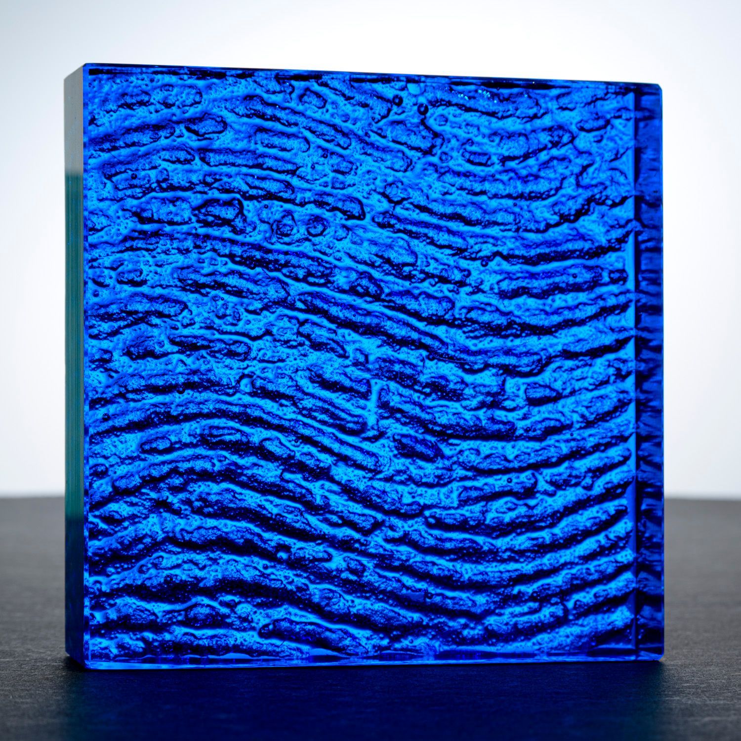 A blue counter top glass block with a wave pattern