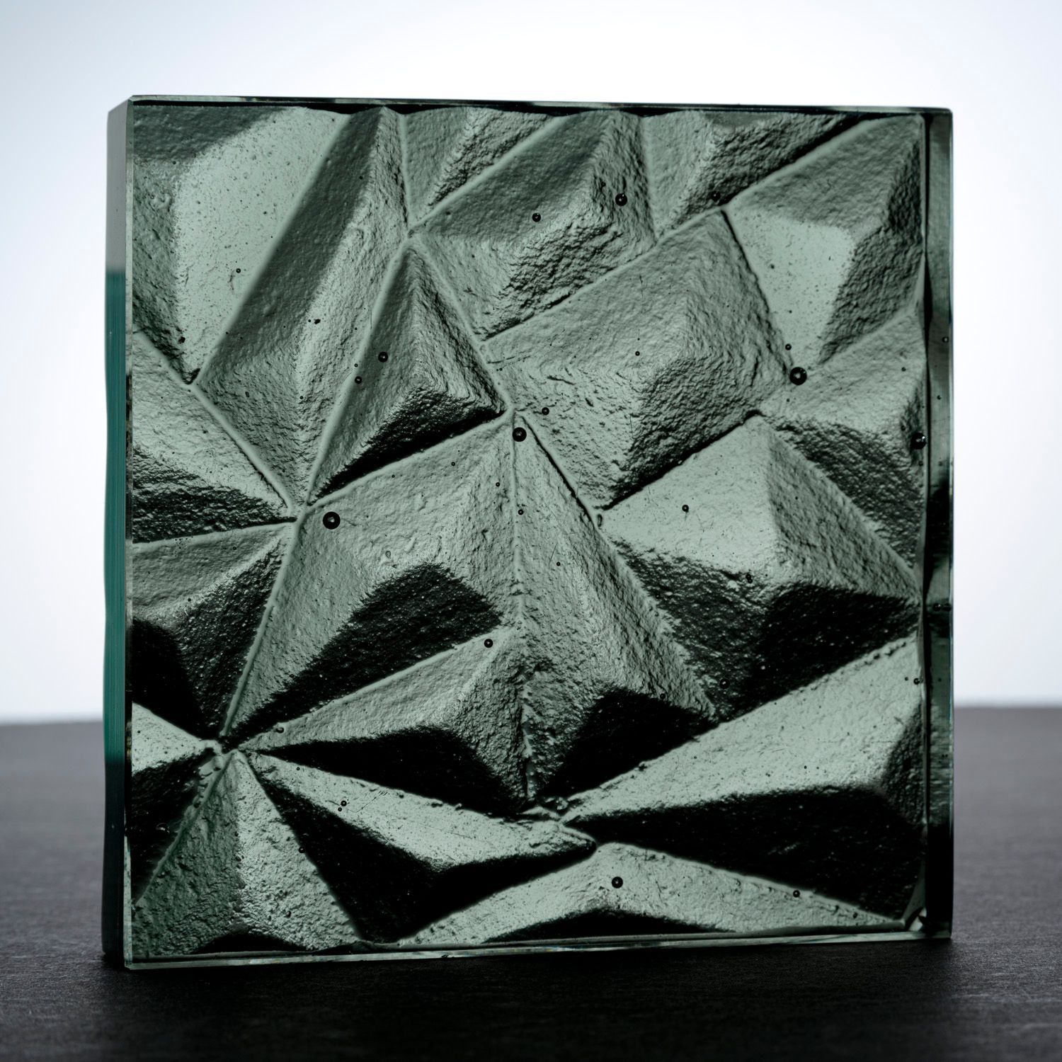 A square piece of olive colored glass counter top with a geometric pattern on it