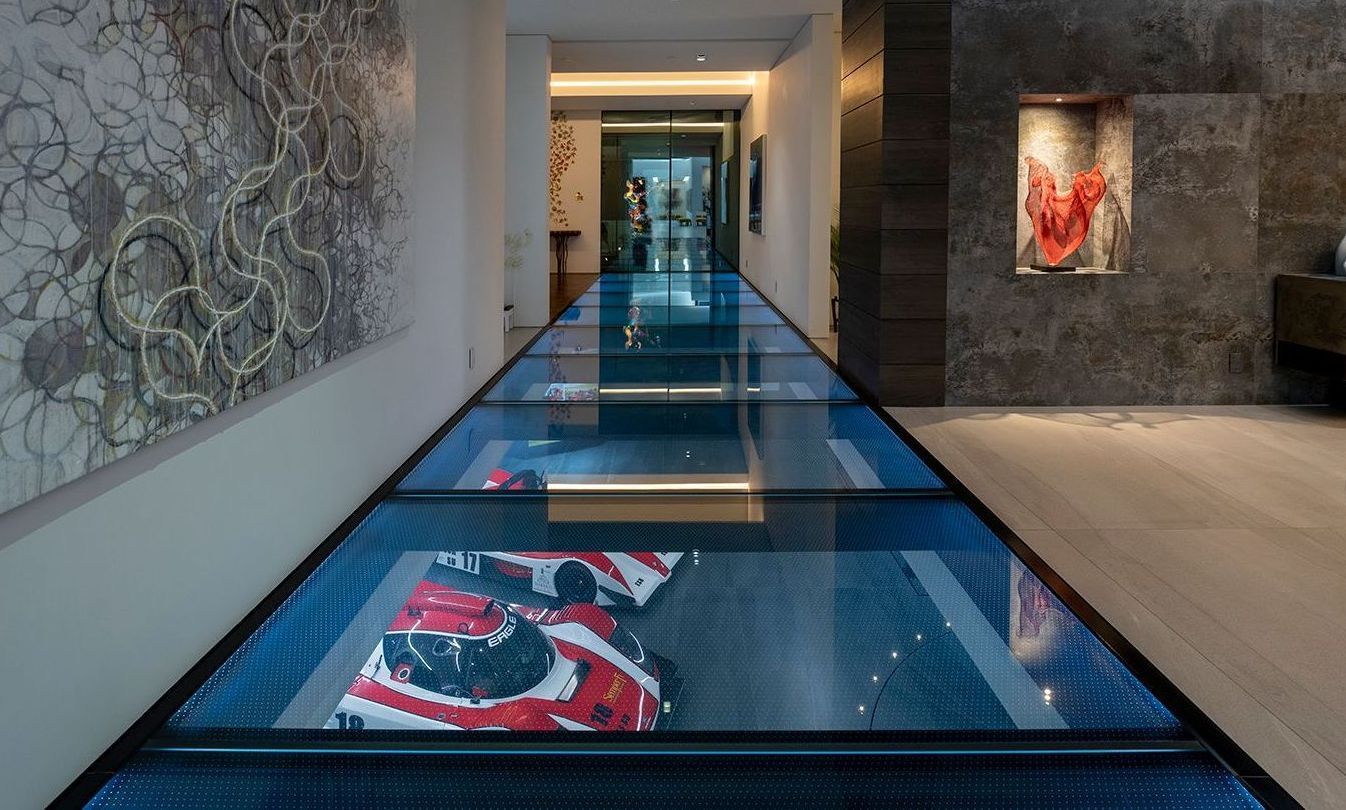 A long hallway with a glass floor displaying cars underneath.