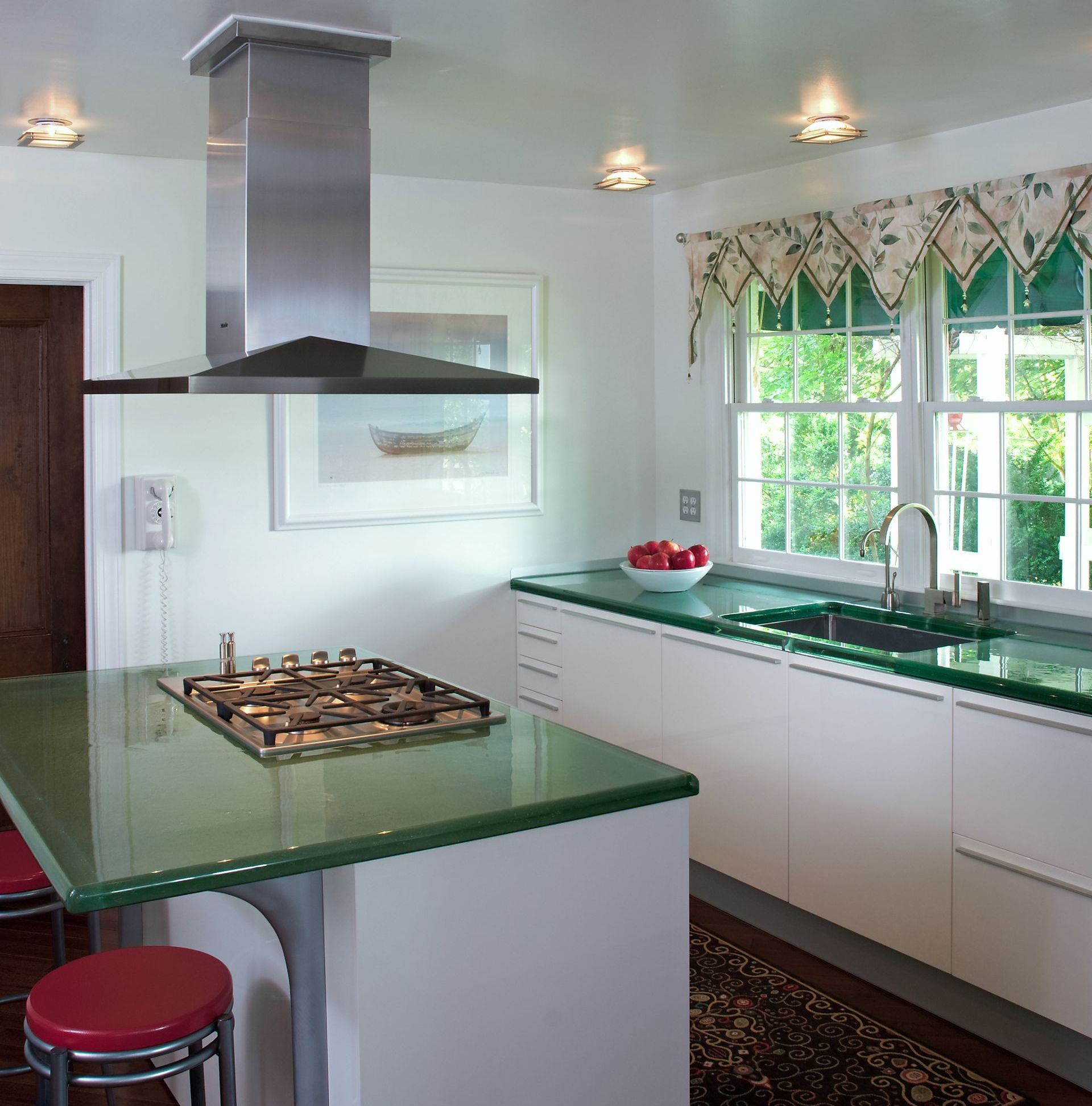 A kitchen with a stove top oven and a sink and green glass counter top