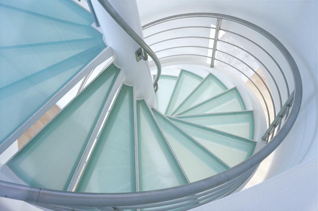 A spiral staircase with clear glass steps and a metal railing