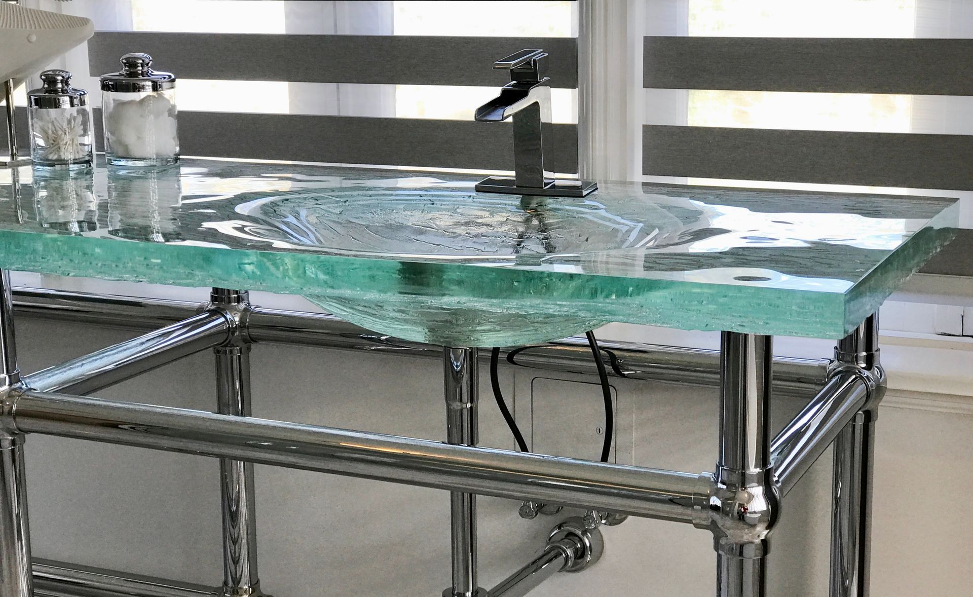 Glass water spill on a metal lab table near a faucet and bottles
