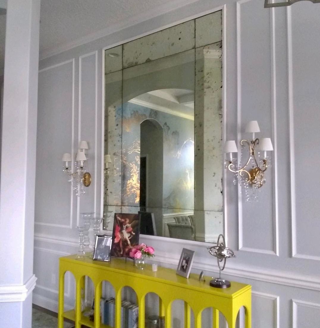 A yellow table in front of a large antique mirror