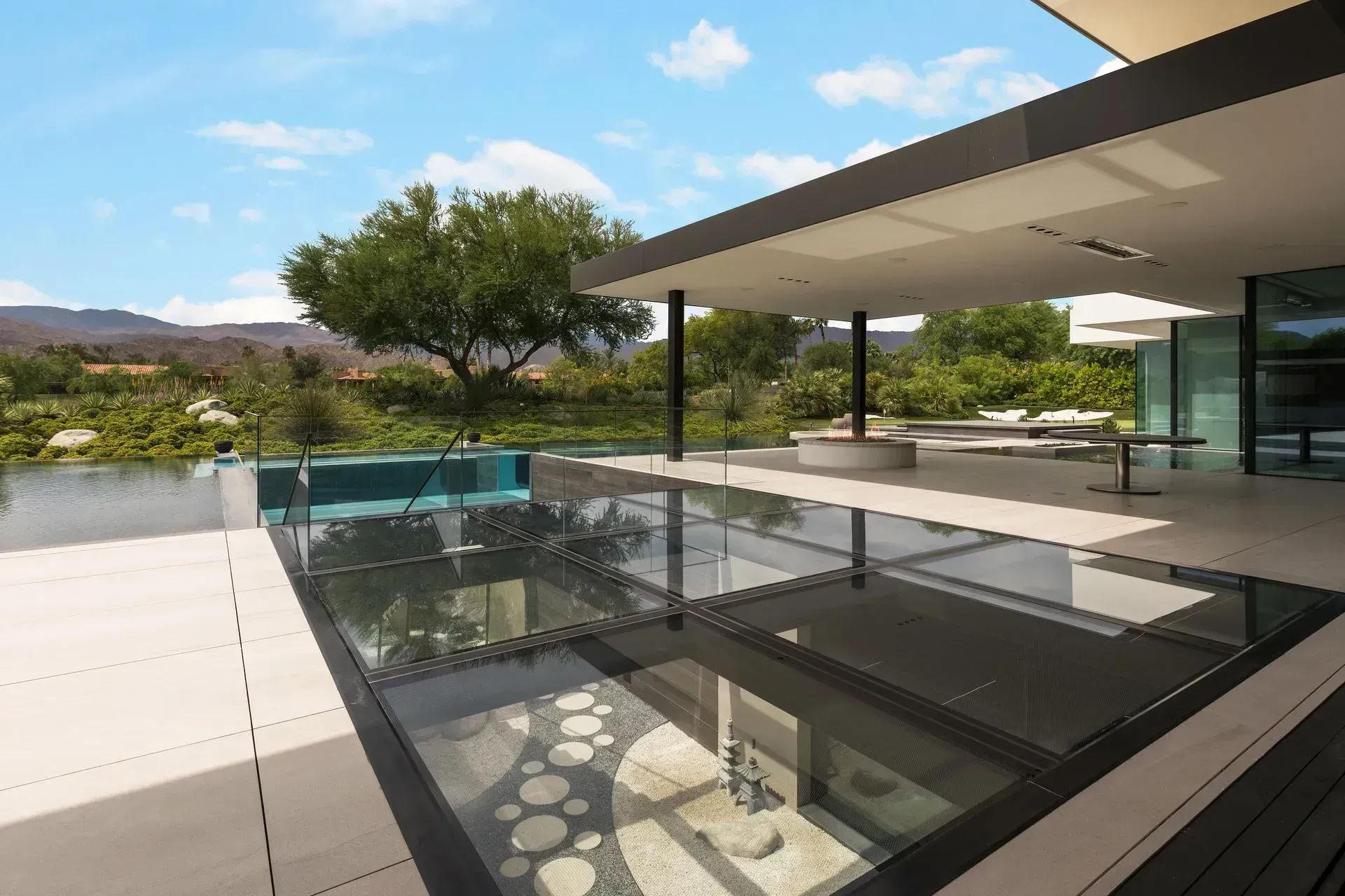 Modern rooftop terrace with glass railings, a pool, and mountain views under a covered patio
