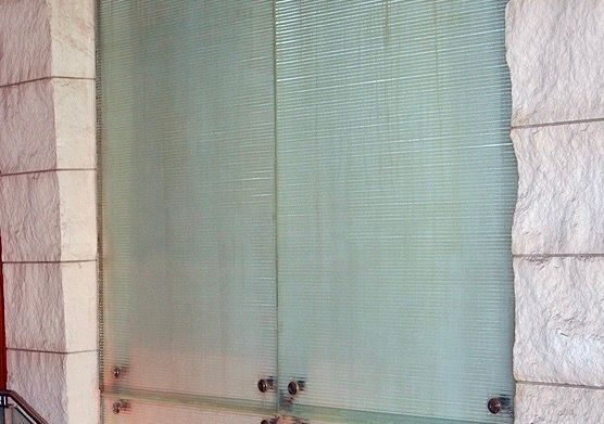 Frosted glass shower door with metal frame and beige stone tile walls