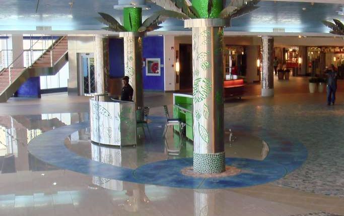A lobby with palm trees and liquid lave floor tiles in the middle of it
