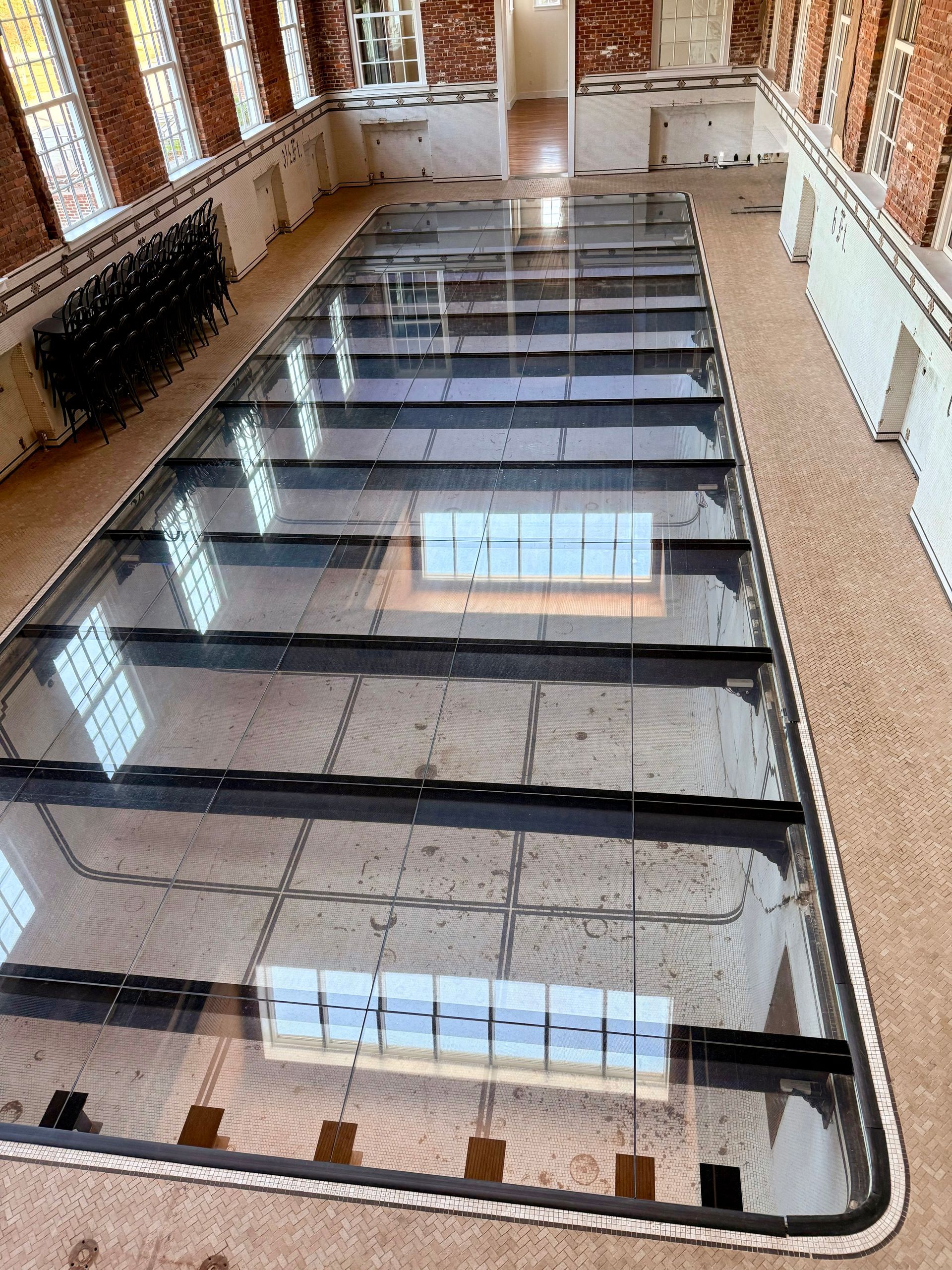 Empty indoor atrium with a long glass floor skylight and brick walls on both sides