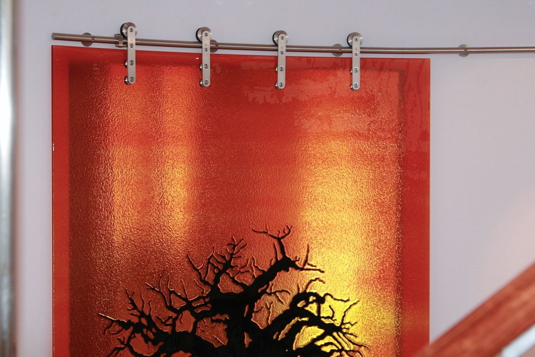 Orange and yellow textured artwork with a silhouetted tree, hanging from a sliding track.