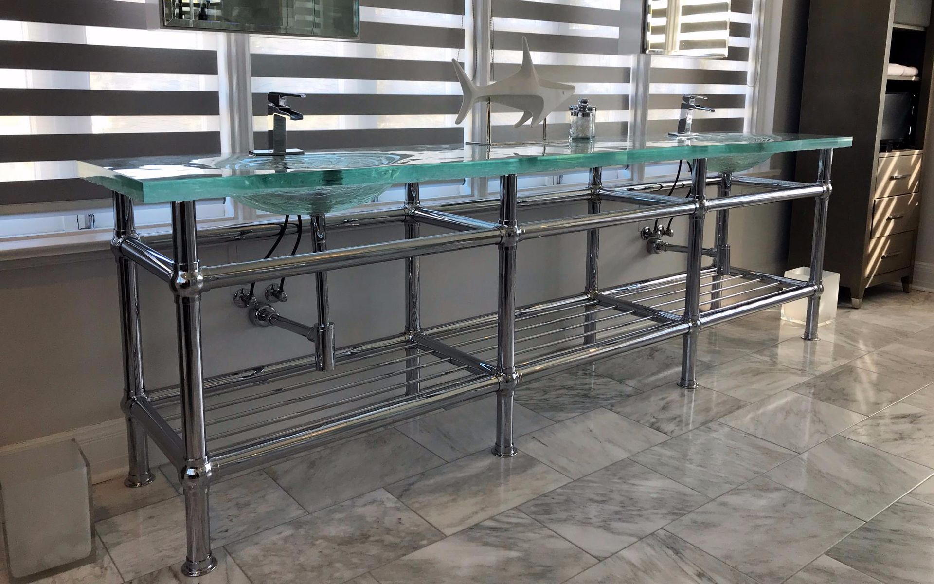 A bathroom sink with a glass table top is sitting on a tiled floor.