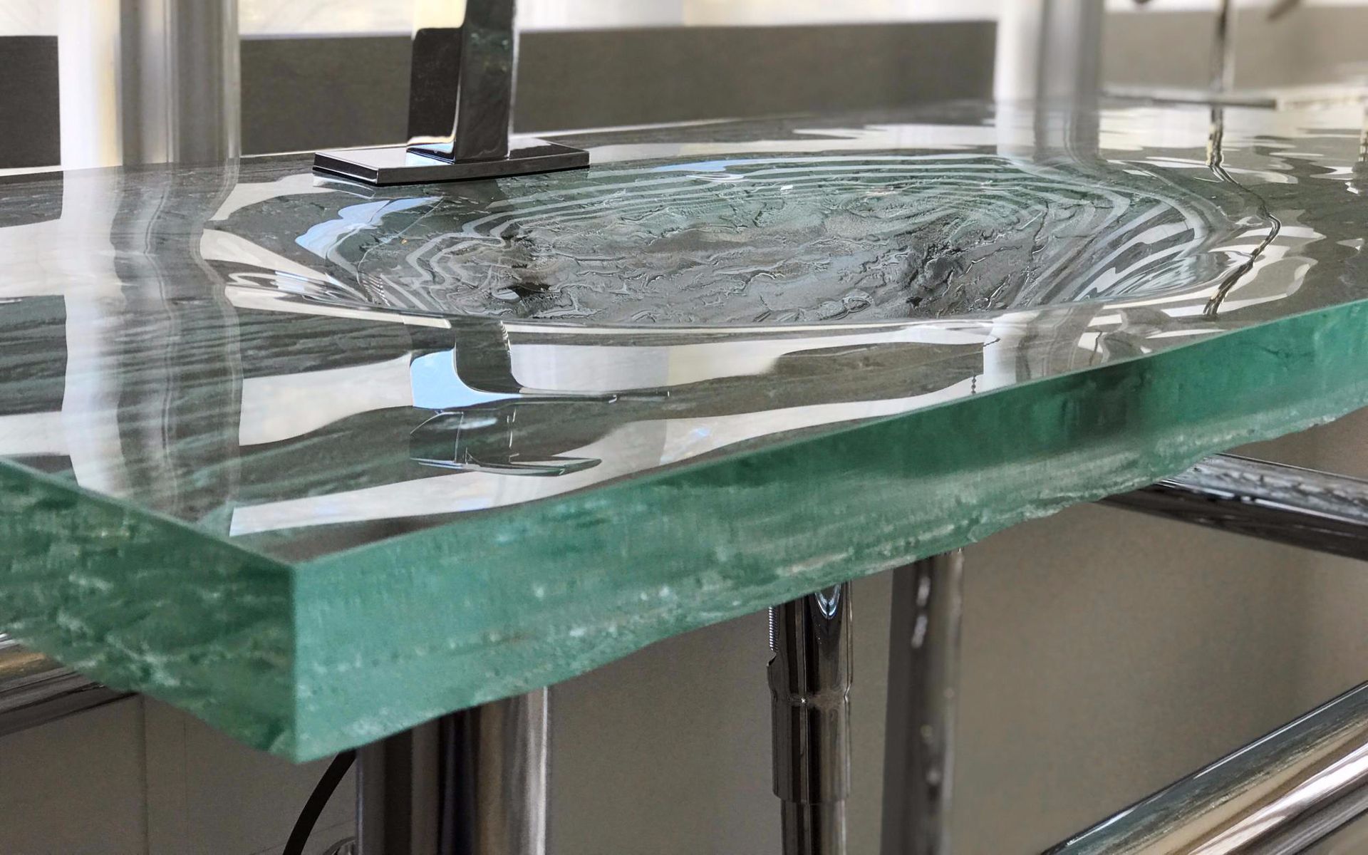 A close up of a glass counter with a sink in the background.