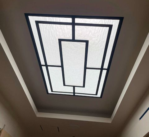 A ceiling with a rectangular skylight framed by black geometric lines.