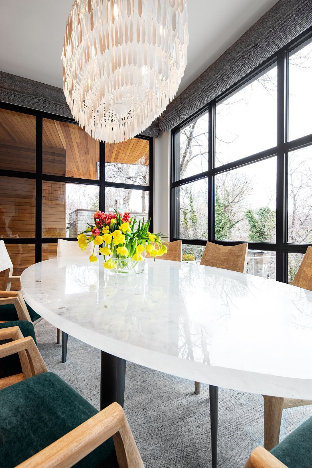 Modern conference room with a large white oval table, colorful flowers, and floor-to-ceiling windows
