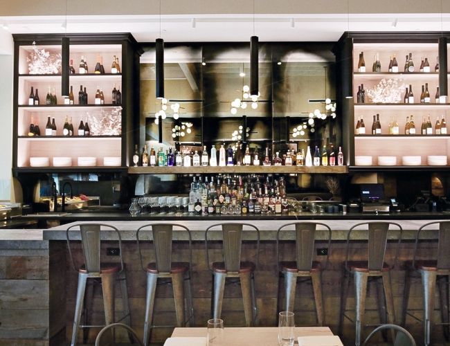 A restaurant with tables and stools and a bar