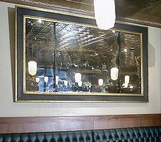 A large framed antique mirror is hanging on a wall in a restaurant.