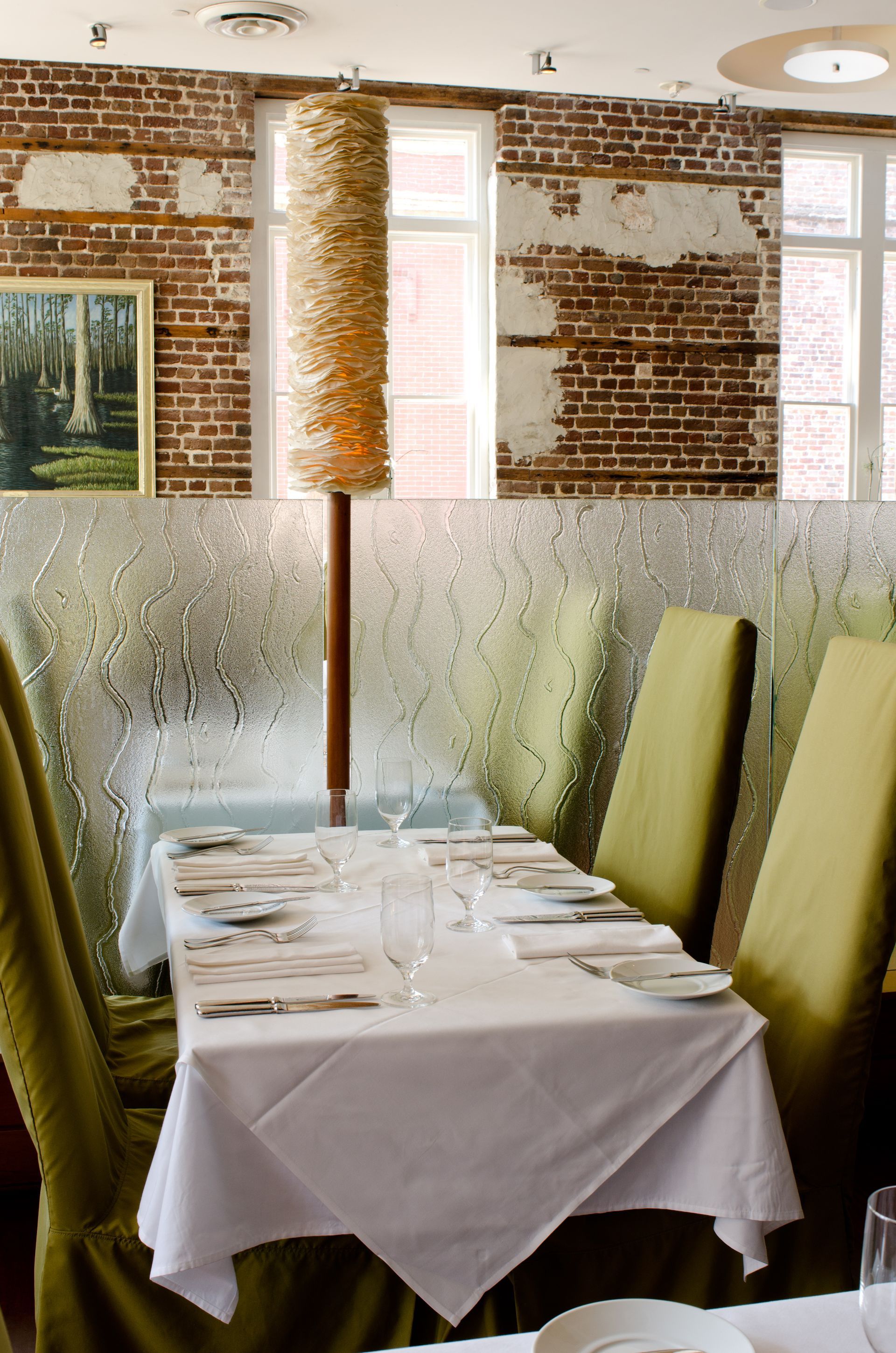 Set dining table beside frosted glass partitions in a bright brick-walled restaurant