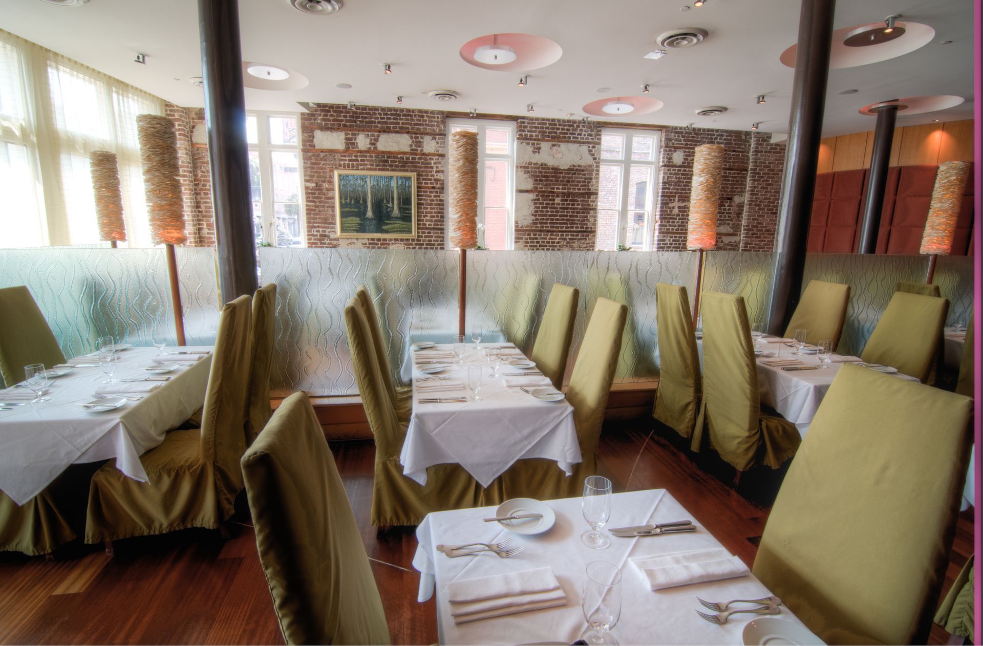 Empty restaurant dining area with neatly set tables, pale chairs, and soft daylight from the windows