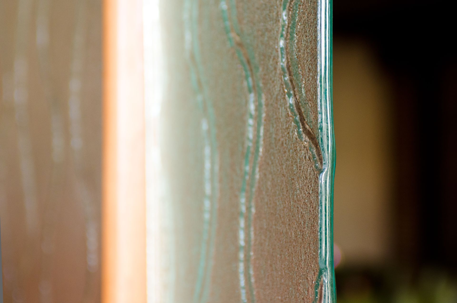 Close-up of a wooden door edge with peeling paint and a blurred dark interior beyond