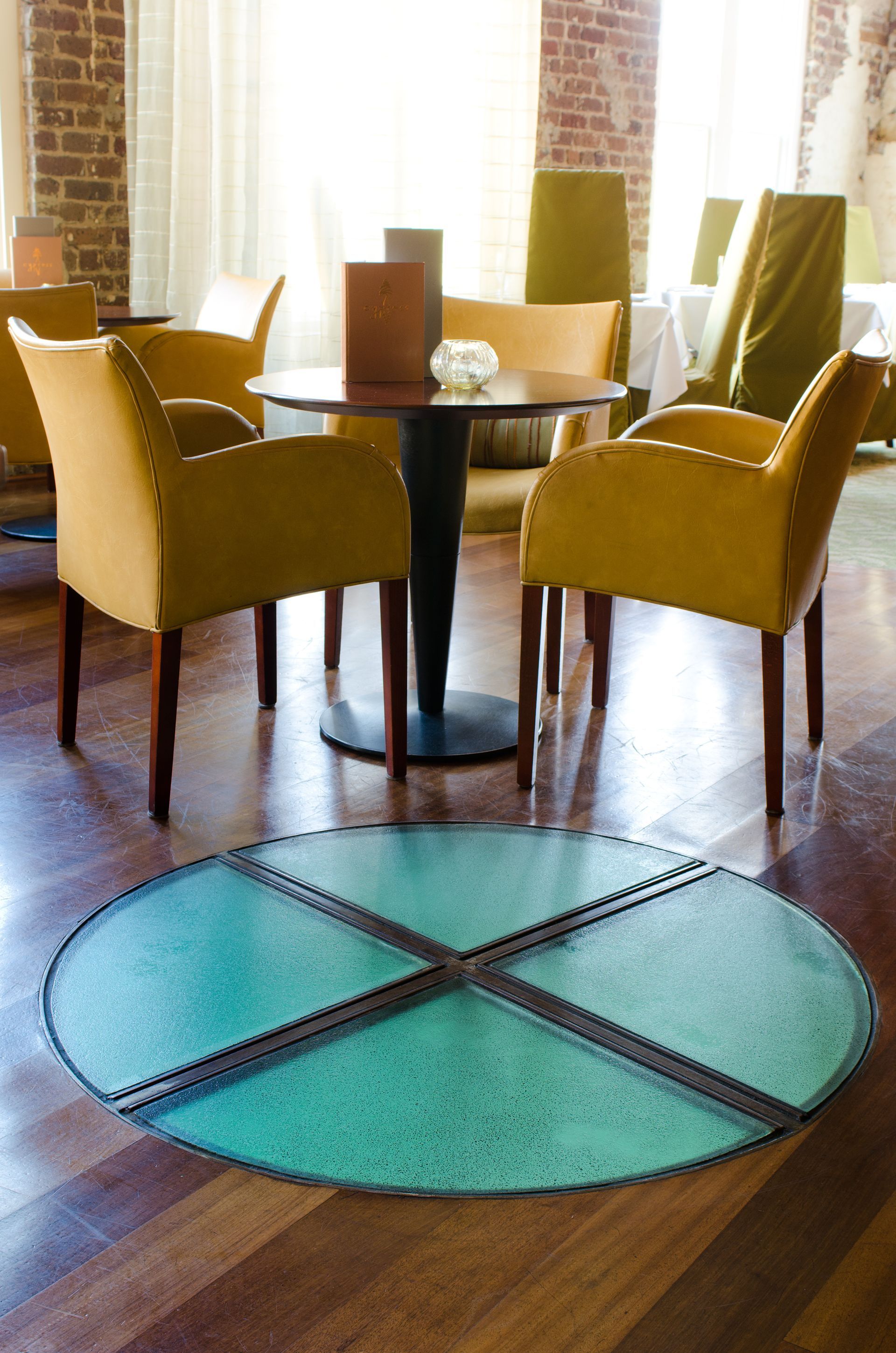Dining table with mustard chairs over a turquoise circular rug on a wooden floor