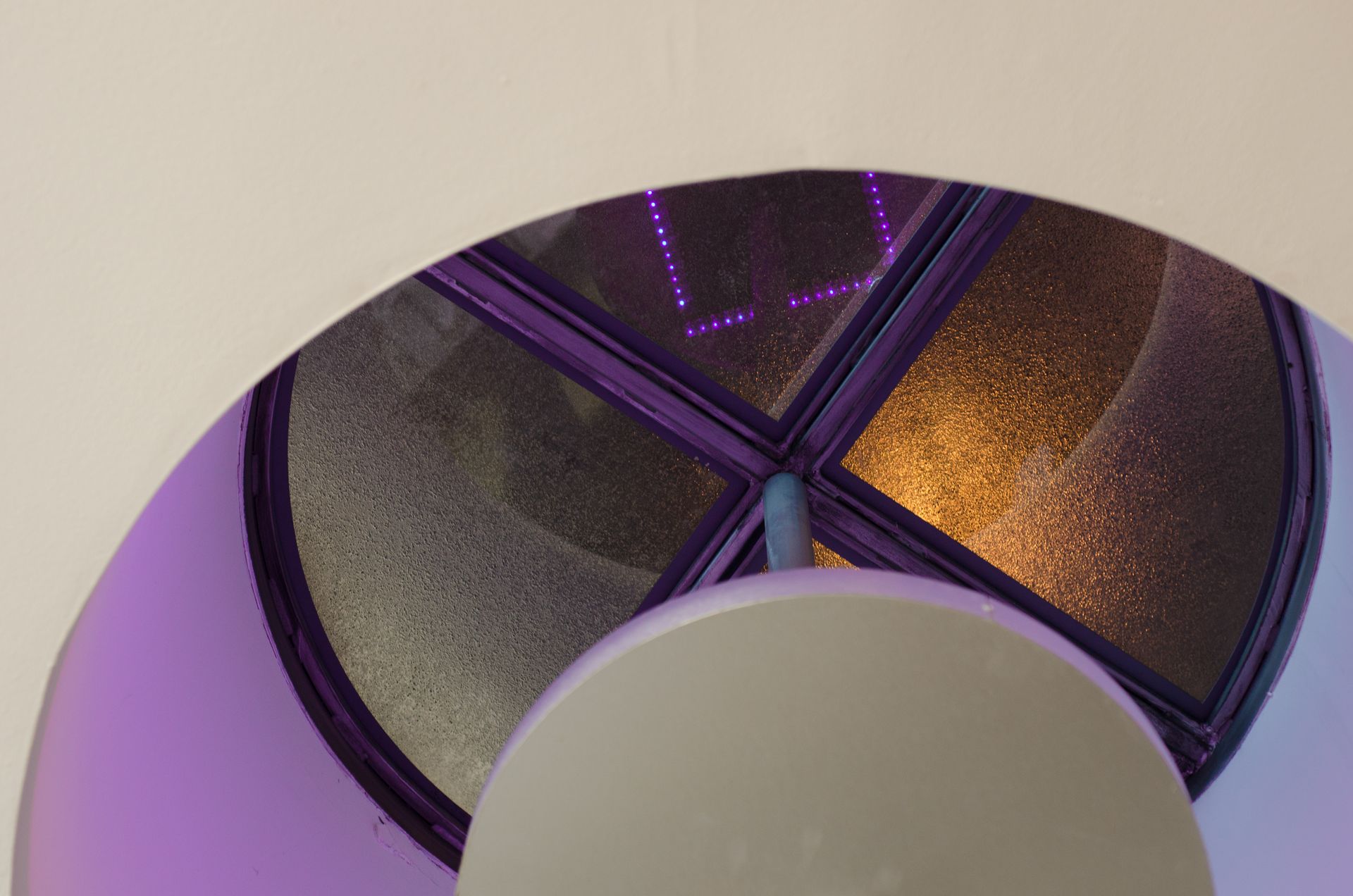 Purple-lit circular ceiling vent with a curved white foreground structure