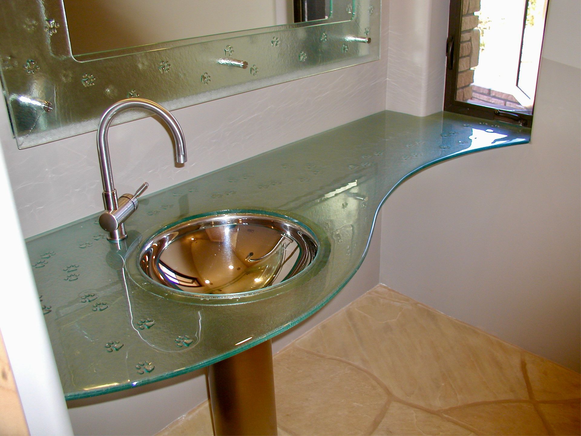 A bathroom glass counter top with a stainless steel sink and a mirror