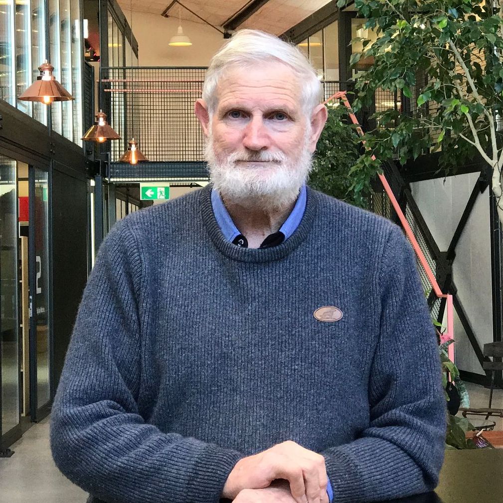Biobusters | A man with a beard is wearing a grey sweater and a blue shirt.