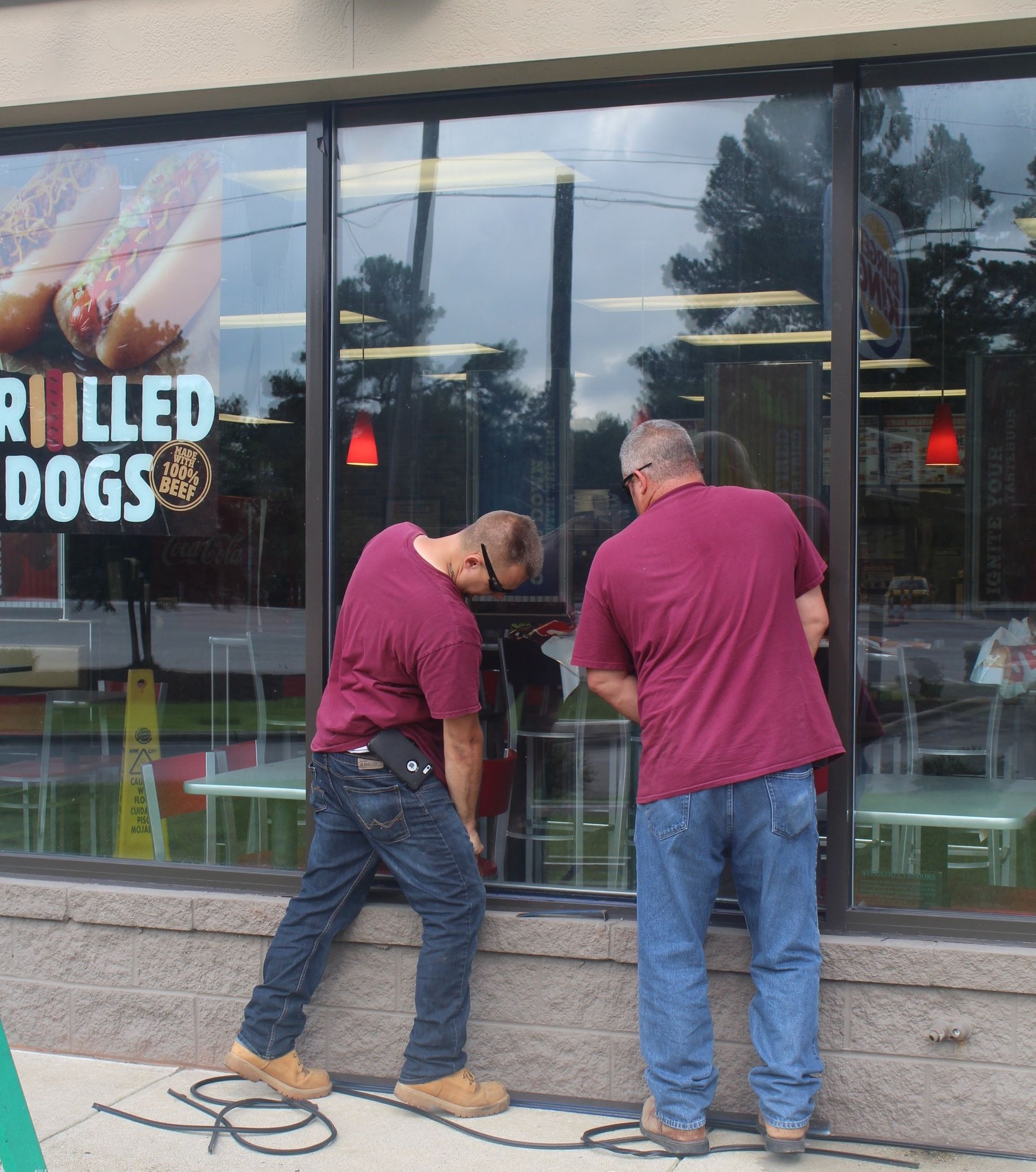Two men standing outside a grilled dogs restaurant