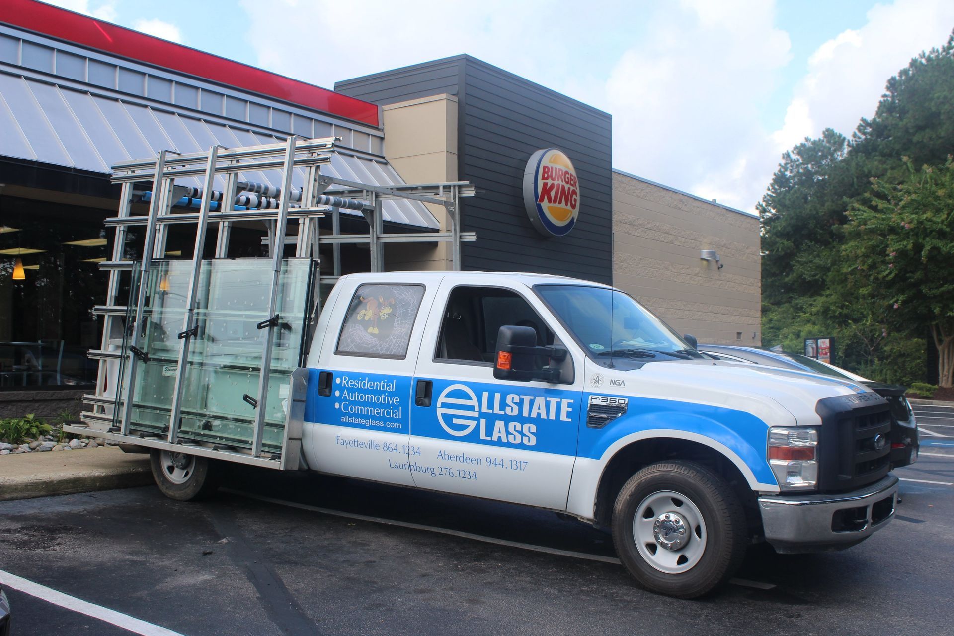 A glass truck is parked in front of a burger king