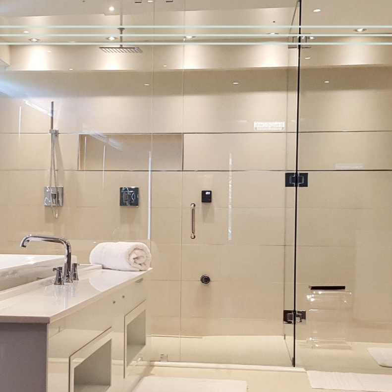 Modern beige bathroom with glass shower, white vanity, sink, and towel roll in Pinehurst, NC