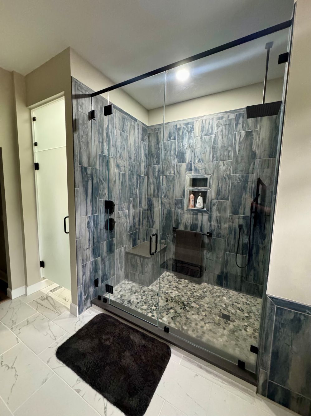 A bathroom with a walk in shower and a glass door.