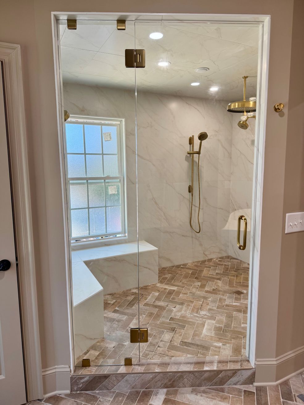 A bathroom with a walk in shower and a glass door.