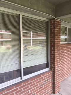 A brick building with a window with blinds on it