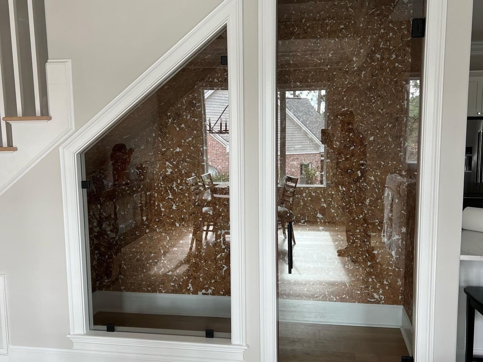 Glass panels with a decorative overlay, framing a dining area visible from a stairwell in Aberdeen, NC.