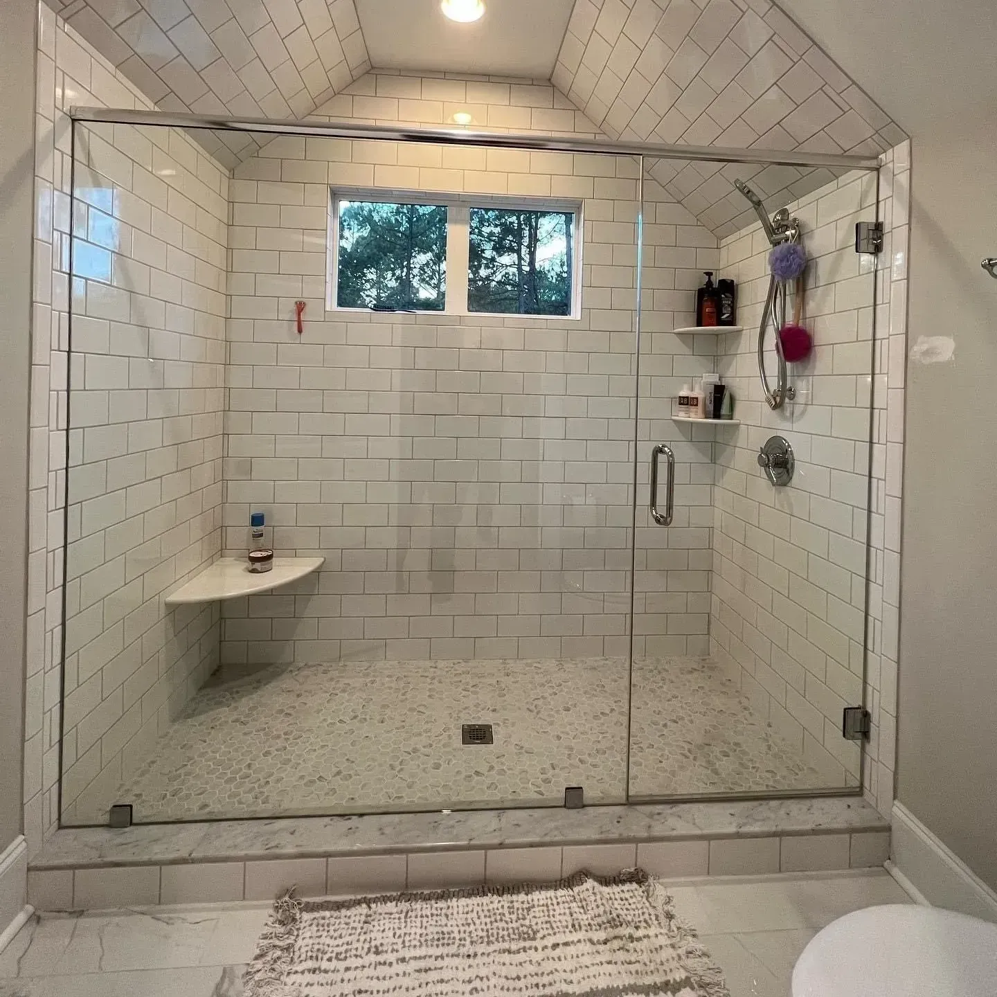 A bathroom with white tiles and a glass shower door