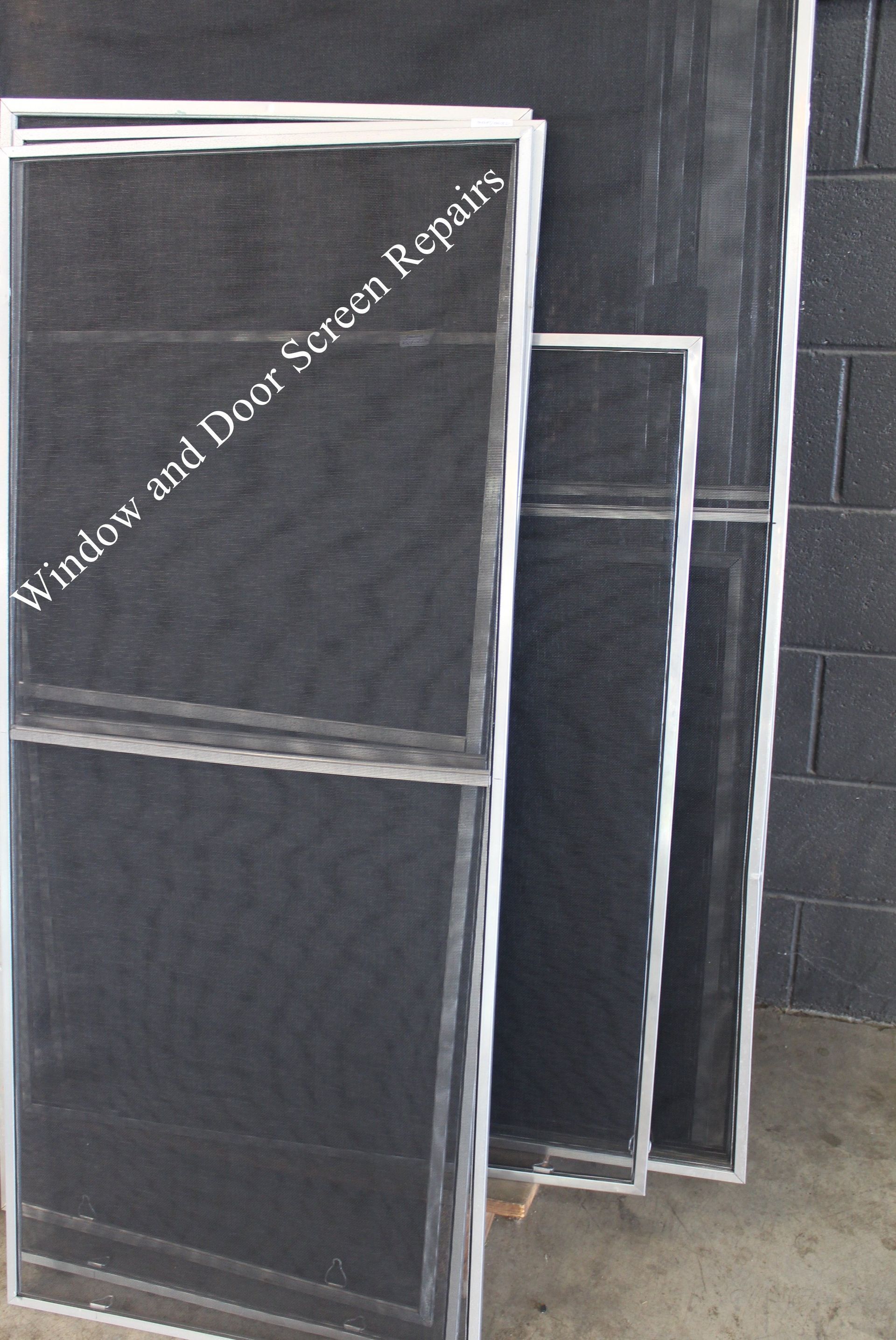 A window and door screen repair sign on a brick wall