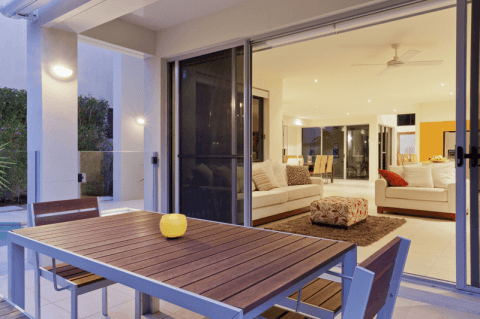A patio with a table and chairs and a sliding glass door leading to a living room.