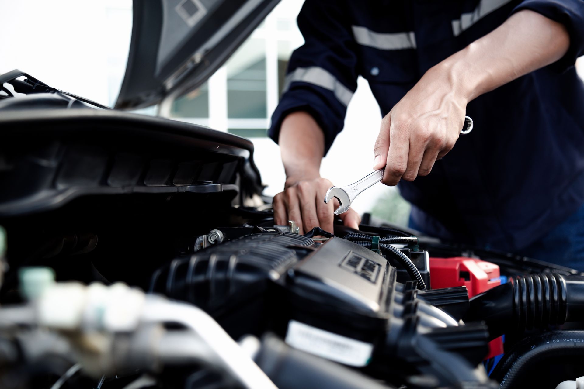 Mechanic tightening a car engine component with a wrench under the hood
