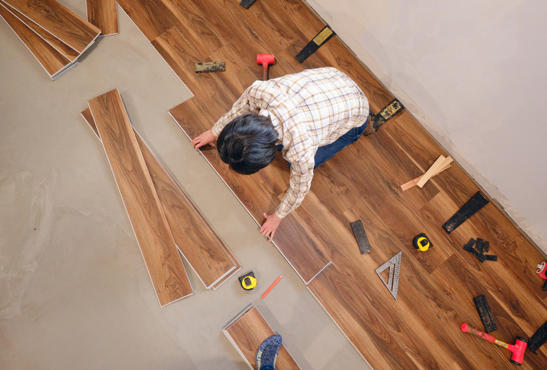 A man is installing a wooden floor in a room.