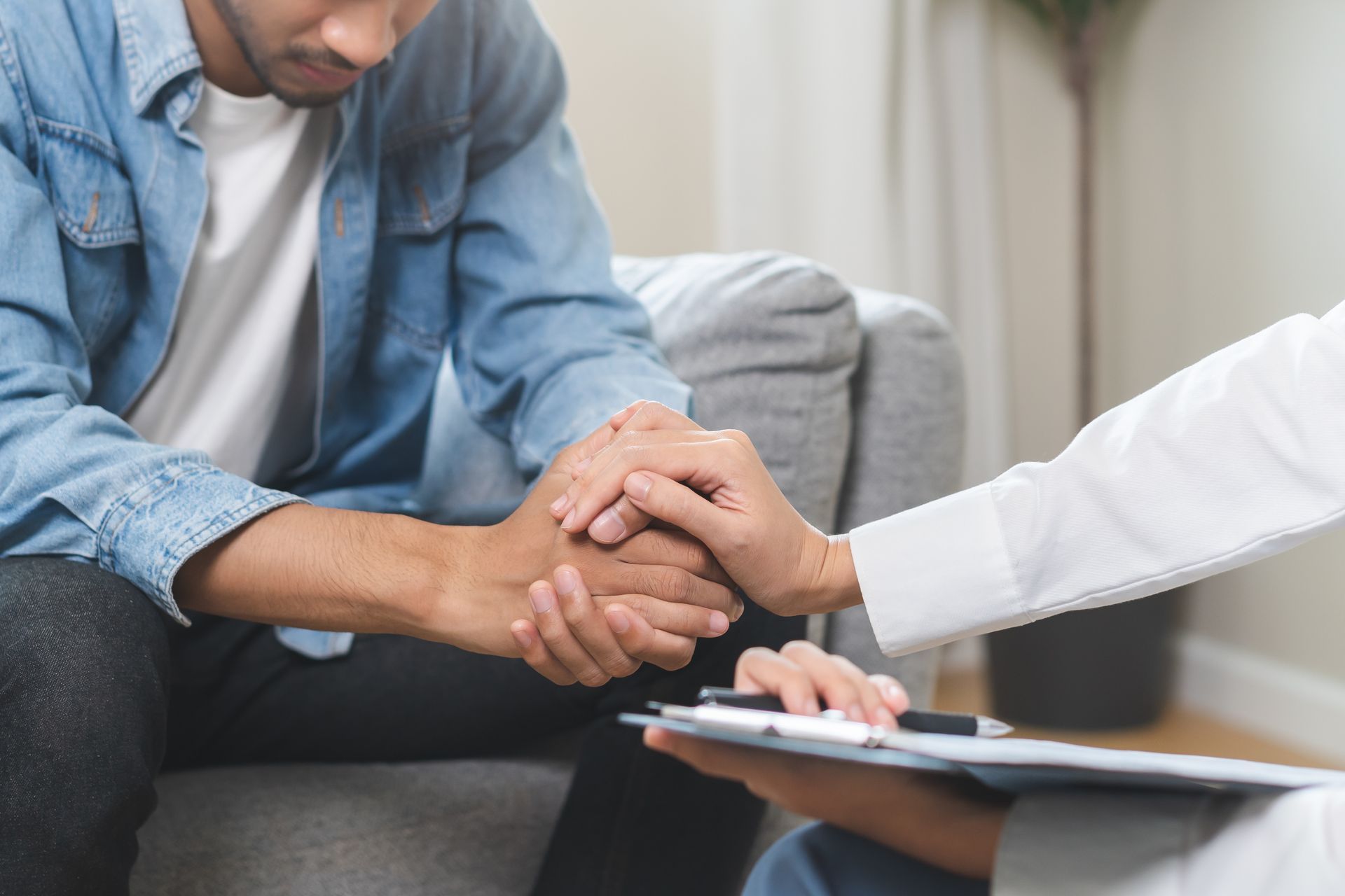 Man sitting, hand held by person with clipboard. Indoor setting, comfort and support. Man sitting, hand held by person with clipboard. Indoor setting, comfort and support.