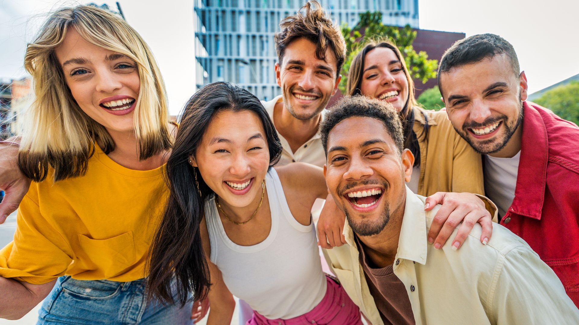Group of smiling people pose for a photo outdoors, near a building. Group of smiling people pose for a photo outdoors, near a building.