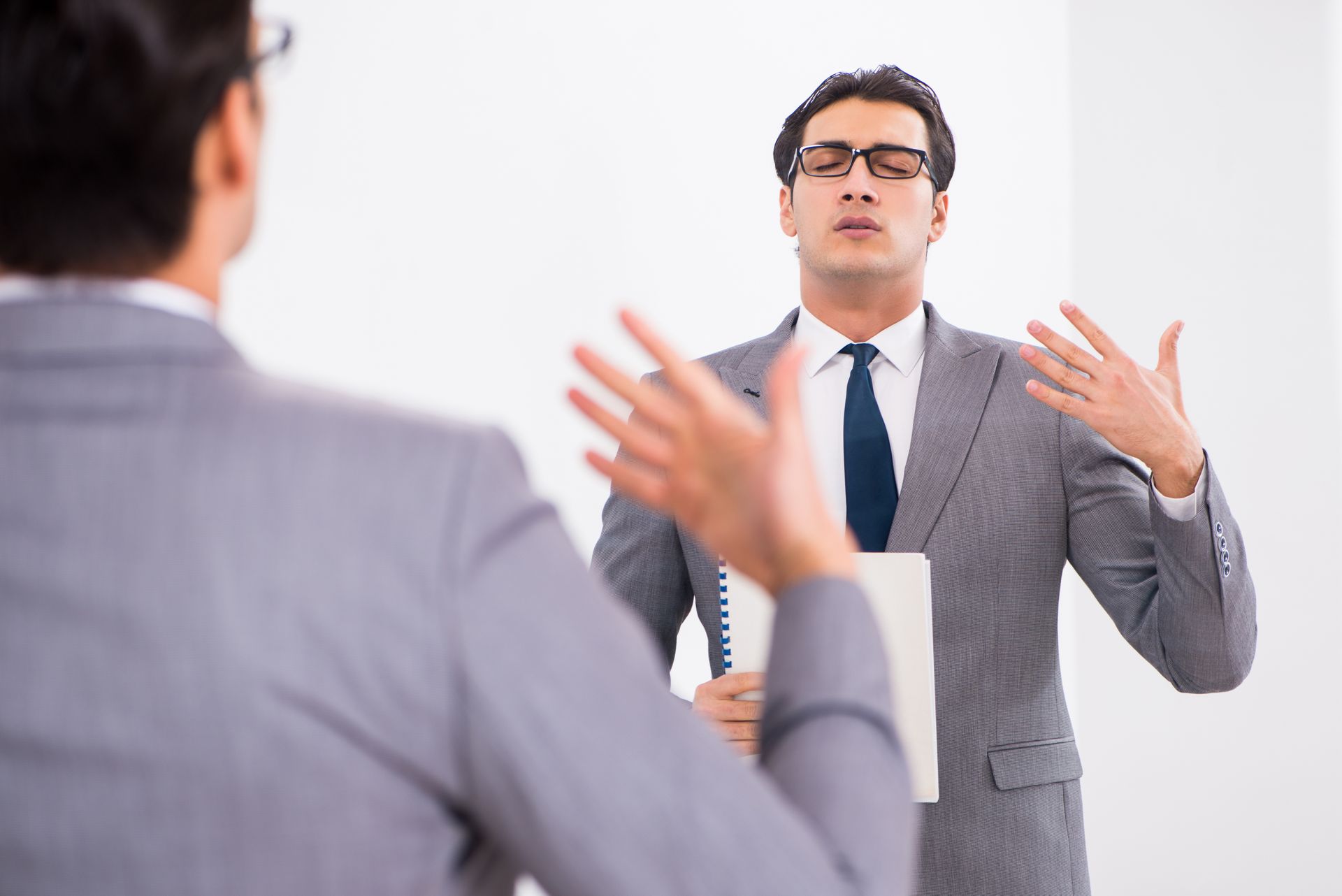 Man in suit gestures with hands as he practices presentation in front of another man. Man in suit gestures with hands as he practices presentation in front of another man.