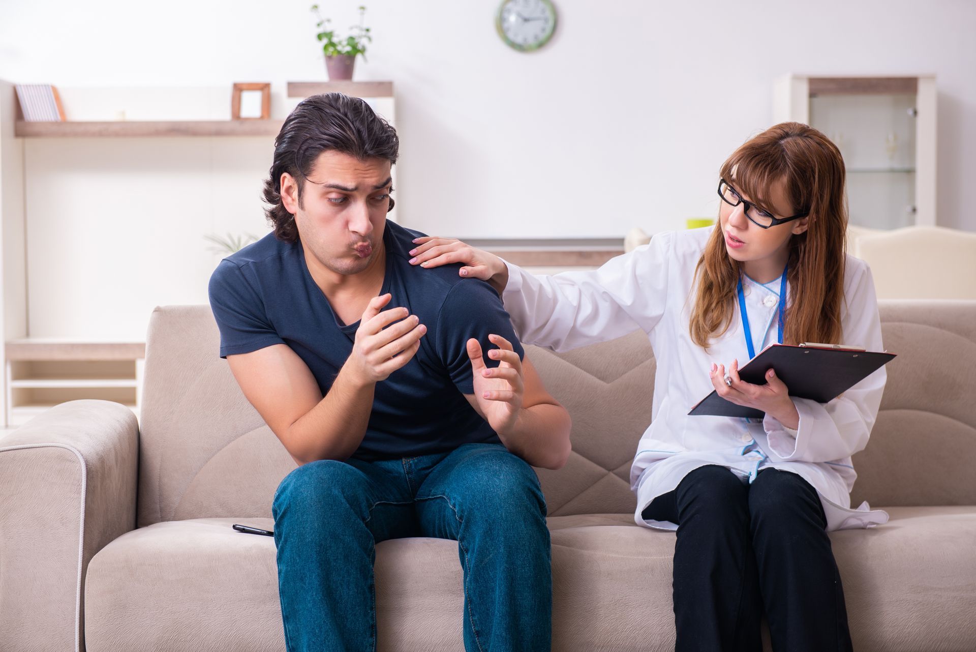 Person on couch being consoled by a person in a lab coat, holding clipboard. Person on couch being consoled by a person in a lab coat, holding clipboard.