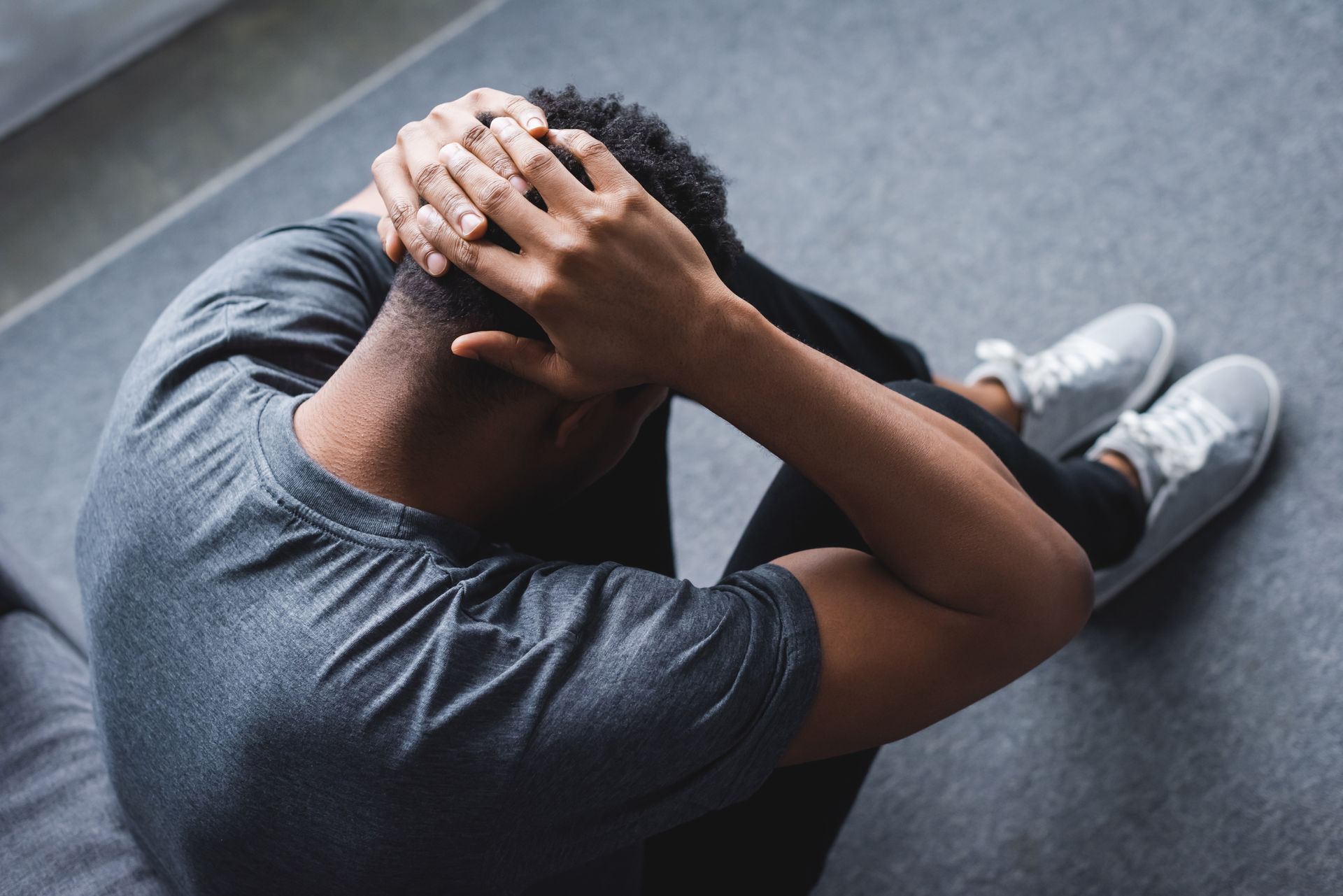 Man with head in hands, sitting on floor, in distress. Man with head in hands, sitting on floor, in distress.