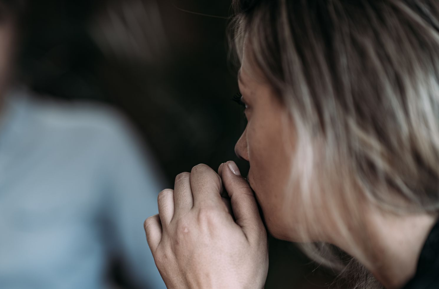 Woman in distress, covering her mouth, talking to therapist in a blurred office setting. Woman in distress, covering her mouth, talking to therapist in a blurred office setting.
