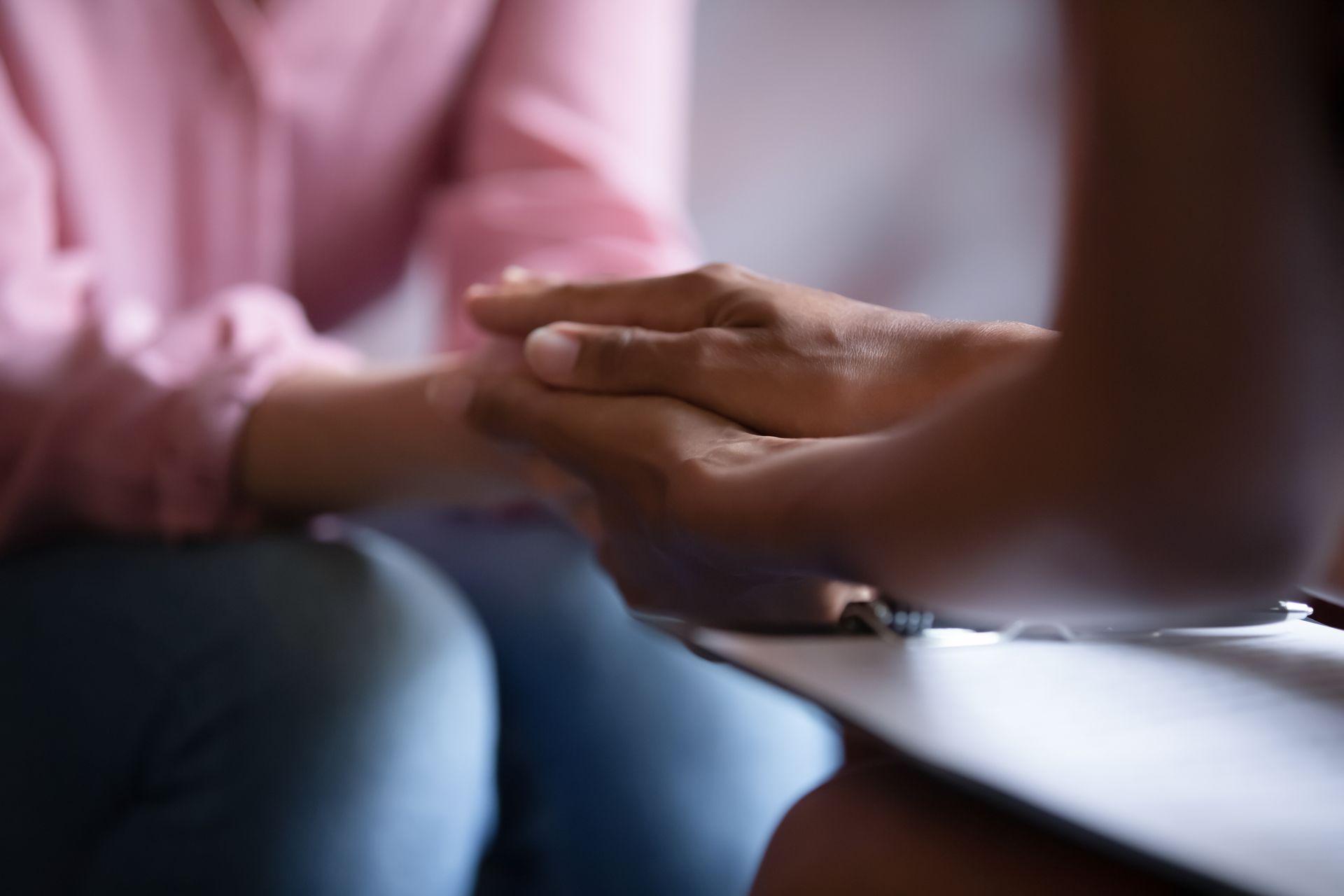 Hands of one person resting on another's, likely offering comfort during a session. Hands of one person resting on another's, likely offering comfort during a session.