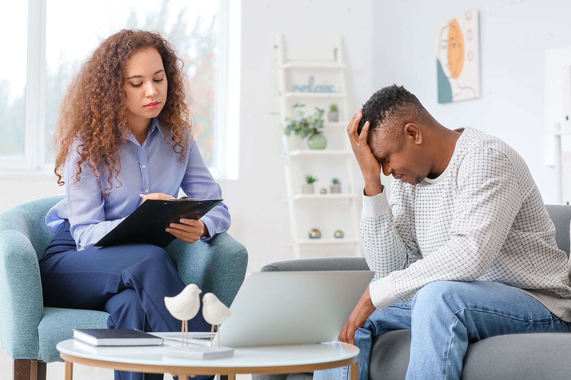Therapist with notepad listens to a person with their head in their hands, in a counseling setting. Therapist with notepad listens to a person with their head in their hands, in a counseling setting.