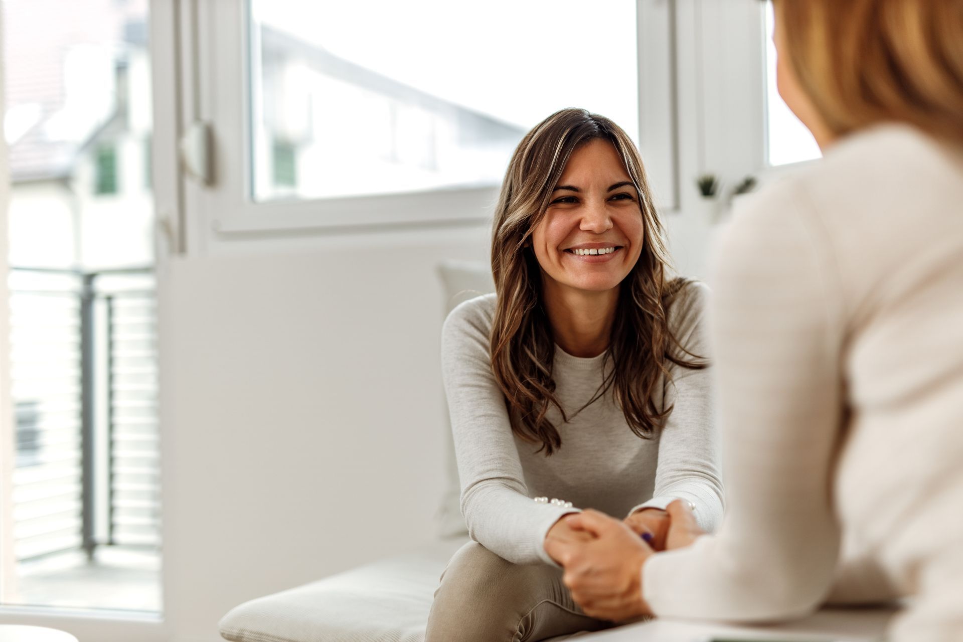 Woman smiling while holding hands with another person in a room. Woman smiling while holding hands with another person in a room.