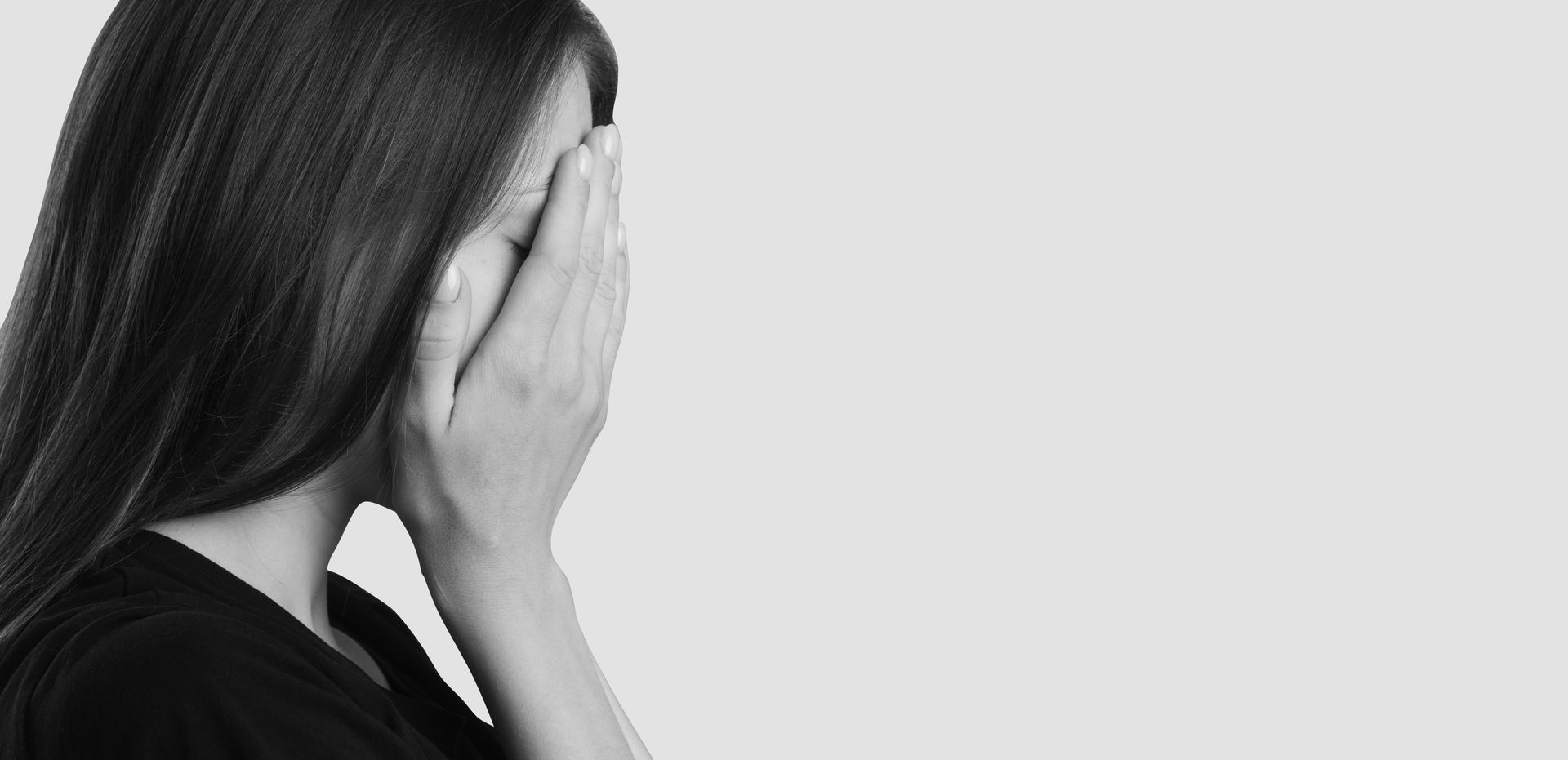 Woman covering face with hands, in profile. Black and white, plain background. Woman covering face with hands, in profile. Black and white, plain background.