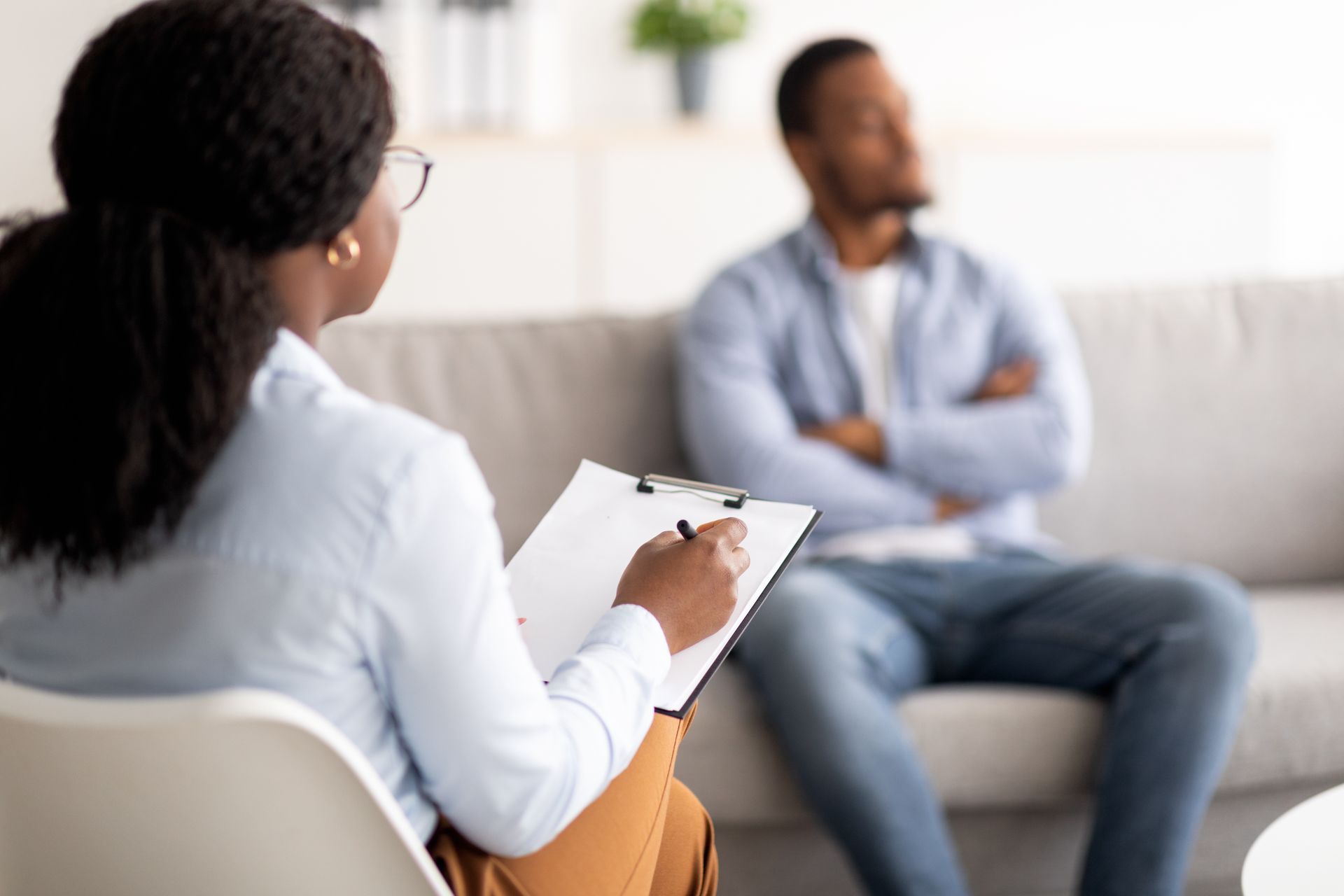 Therapist taking notes, consulting with person sitting on a sofa. Therapist taking notes, consulting with person sitting on a sofa.