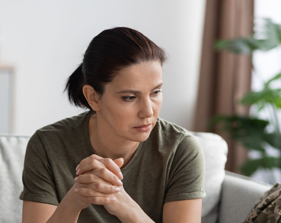 Woman in military fatigues on a sofa, looking pensive during a therapy session. Woman in military fatigues on a sofa, looking pensive during a therapy session.