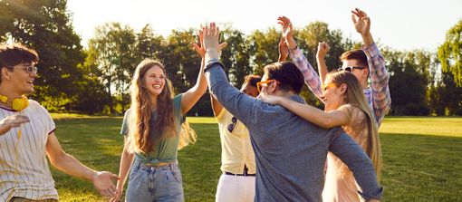 Group of people celebrating in a park, raising their arms and smiling. Sunlight, green grass, and trees. Group of people celebrating in a park, raising their arms and smiling. Sunlight, green grass, and trees.